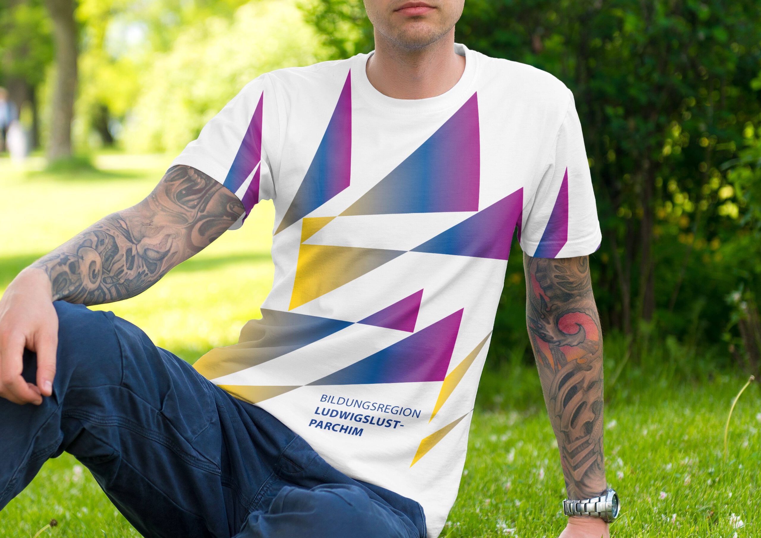 Mockup von einem T-Shirt für die Bildungsregion LUP im neuen Corporate Design von Daniel Roode. Mann auf Wiese. Branddesign